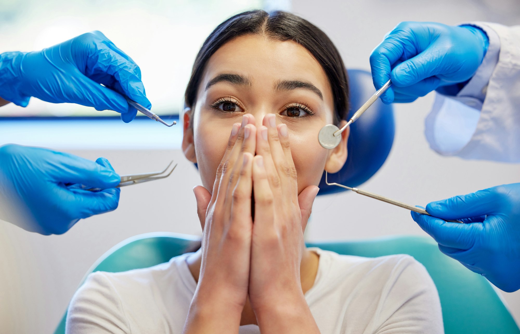 Shot of a young woman experiencing anxiety while having a dental procedure performed on her