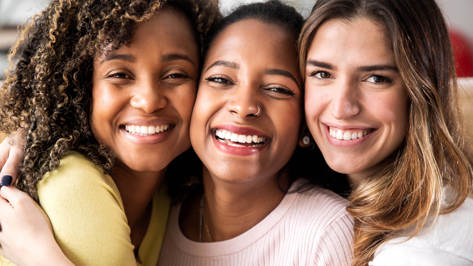 Three female friends with radiant smiles, symbolizing the confidence and happiness that dental implants from Bright Choice Dentistry can restore.